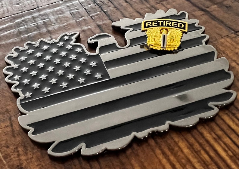 May include: A black and silver metal American flag shaped like an eagle with a gold "Retired" patch on the eagle's chest.