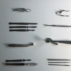 Może przedstawiać: Zestaw dziewięciu instrumentów chirurgicznych, w tym skalpele, pincety i narzędzie dentystyczne. Instrumenty wykonane są ze stali nierdzewnej i mają polerowane wykończenie.