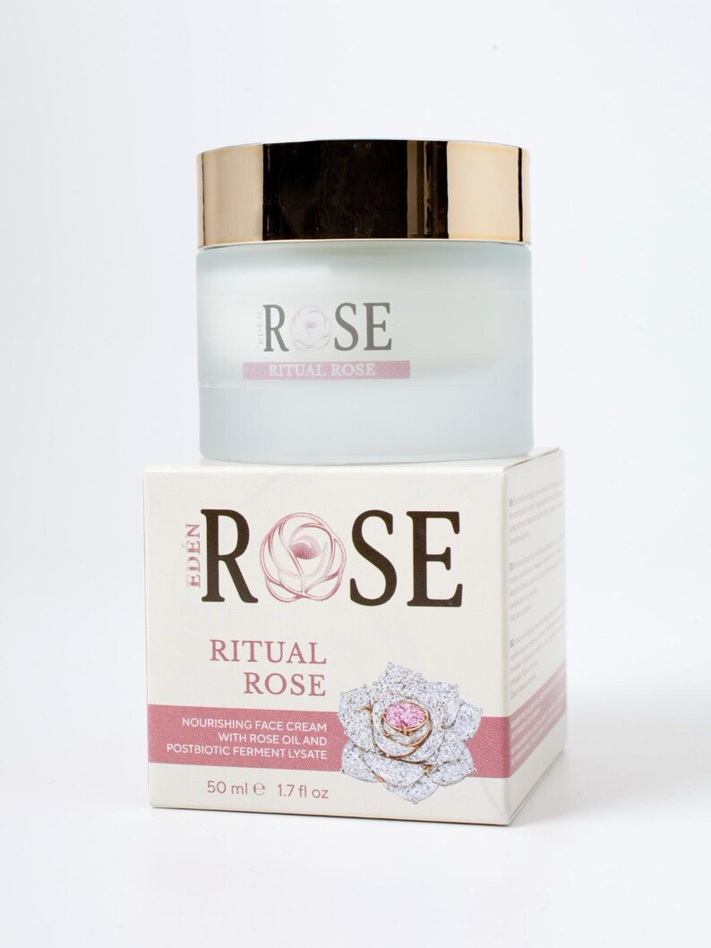 May include: A frosted glass jar of Eden Rose Ritual Rose nourishing face cream with a gold lid, sitting atop its square cardboard box. The packaging features the text "Eden Rose Ritual Rose" and "50 ml 1.7 fl oz" with a rose illustration.