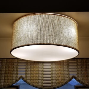 May include: A round, woven, light fitting with a white inner shade. The fitting is hanging from the ceiling and has a natural, beige colour.