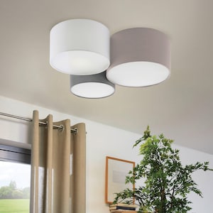 May include: Three round ceiling light fixtures with fabric shades. The shades are white, grey, and a light beige colour.
