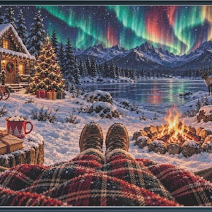 May include: A winter scene featuring a person covered by a red and black plaid blanket, wearing brown boots, sitting by a campfire. In the background, a snow-covered log cabin, a lit Christmas tree, a frozen lake, and the aurora borealis.