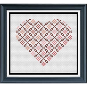 Puede incluir: Obra de arte en punto de cruz enmarcada que representa un corazón. El corazón está formado por un patrón repetitivo de cuadrados en tonos marrones y rosas. La obra está sobre un fondo blanco y enmarcada en un marco azul oscuro.