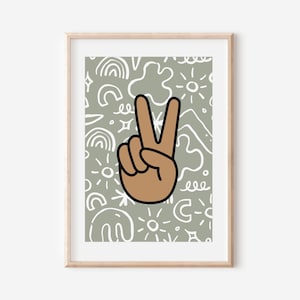 May include: A framed print with a green background and white abstract shapes. A brown hand with two fingers raised in a peace sign is in the center of the print.