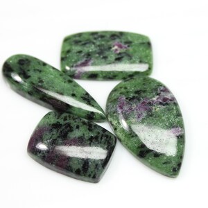 May include: Four green, black, and purple gemstone cabochons. The cabochons are cut in different shapes, including oval, teardrop, and rectangular.