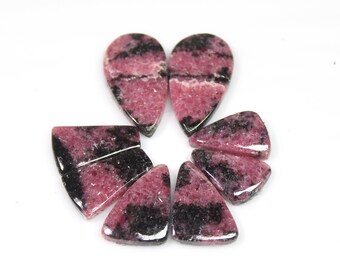May include: A collection of eight pink and black gemstone cabochons in various shapes, including teardrop and triangular shapes.
