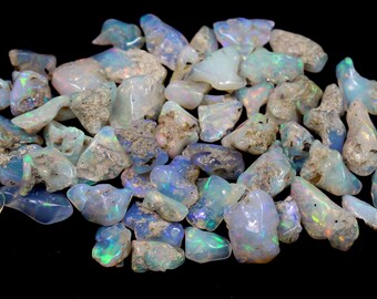 May include: A collection of rough, natural opal stones. The opals are a mix of white, blue, and green with iridescent flashes of colour.