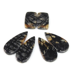 May include: Five natural stone cabochons in a teardrop and rectangular shape. The stones are black with brown and white veins.