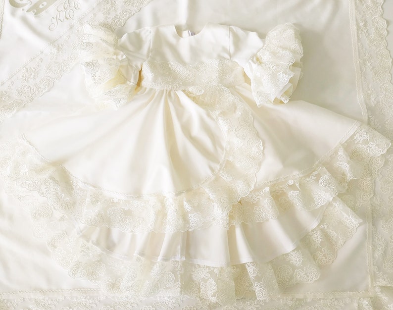 May include: A white, lace-trimmed dress with a ruffled skirt. The dress is made of a soft, flowing fabric and has a simple, elegant design.