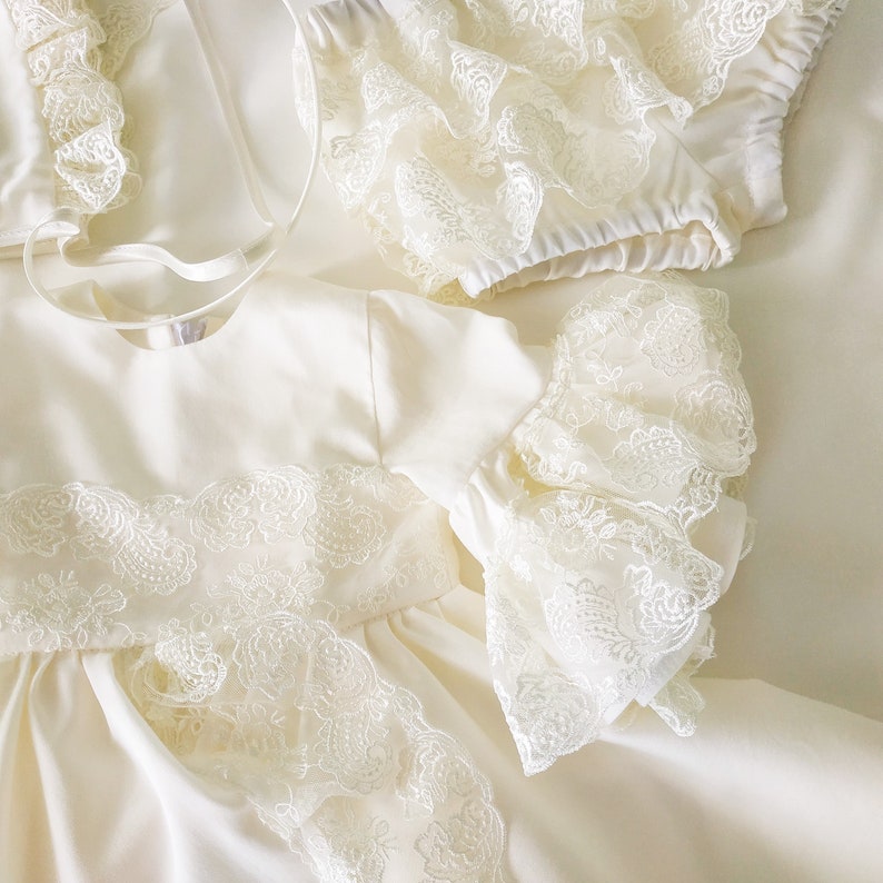 May include: A white satin dress with lace trim and ruffled sleeves. The dress has a simple, elegant design and is perfect for a special occasion.
