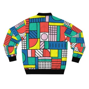 May include: A colorful geometric patterned bomber jacket with a black collar and cuffs. The pattern features various shapes and colors, including red, blue, yellow, green, and pink.