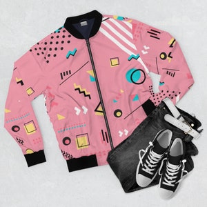 May include: A pink bomber jacket with a geometric pattern in black, white, yellow, blue, and pink. The jacket has a zipper closure and a ribbed collar, cuffs, and waistband.