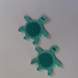 May include: Two crocheted teal green turtle ornaments with black eyes.