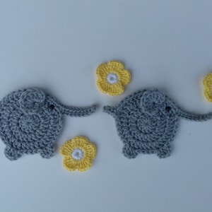 May include: Two gray crocheted elephants with black eyes and yellow crocheted flowers.