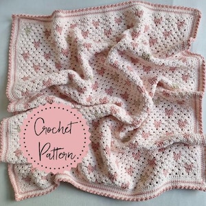May include: A crocheted blanket with a heart pattern in shades of pink and white. The blanket has a scalloped edge and the words "Crochet Pattern" on a pink circle.