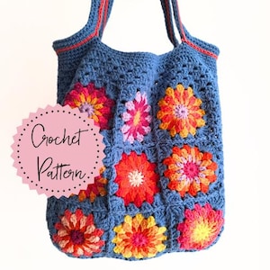 Op de afbeelding: Een gehaakte tote bag met een blauwe basis en kleurrijke bloemenmotieven. De tas heeft een rode bies en twee hengsels. De tekst "Crochet Pattern" staat op een roze cirkel.