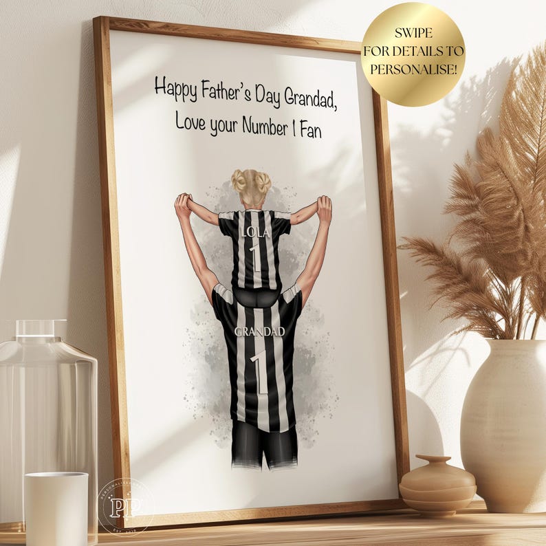 Puede incluir: Una impresi&oacute;n enmarcada con una conmovedora ilustraci&oacute;n. Representa a una persona llevando a un ni&ntilde;o sobre sus hombros, ambos con camisetas a rayas blancas y negras con el n&uacute;mero 1. El texto dice: "Happy Father's Day Grandad, Love your Number 1 Fan."