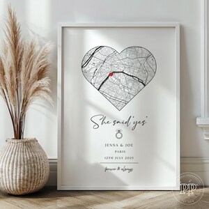 May include: A framed print featuring a heart-shaped map of Paris with a red dot. Text includes "She said yes," names, date, and "forever & always." The print is in a white frame.