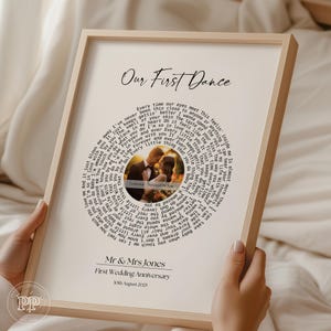 May include: A framed print with the title "Our First Dance". The print has a circular design of song lyrics surrounding a photo of a couple. The bottom of the print reads "Mr & Mrs Jones, First Wedding Anniversary, 30th August 2025."