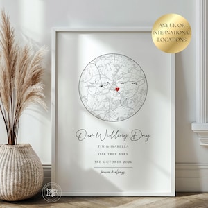 May include: A framed white wall art print featuring a circular black and white map with a red heart icon. The text reads Our Wedding Day, Tim & Isabella, Oak Tree Barn, 3rd October 2026, and forever & always. A gold circular badge states ANY UK OR INTERNATIONAL LOCATIONS.
