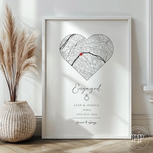 May include: A white framed print featuring a heart-shaped map of Paris, France, with a red marker. The text reads "Engaged", followed by names, date "12th July 2025", and the phrase "forever & always".