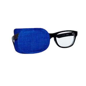 Puede incluir: Un parche para el ojo azul unido a unas gafas con montura negra. El parche para el ojo está hecho de una tela suave y texturizada.