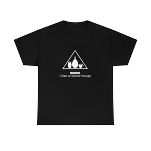 Peut inclure: T-shirt noir avec un panneau d'avertissement blanc qui dit "ATTENTION J'aime lancer des choses". Le panneau représente un vase en poterie et deux tasses.