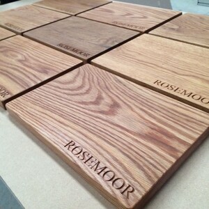 May include: A set of six wooden cutting boards with the text "Rosemoor" engraved on each board.