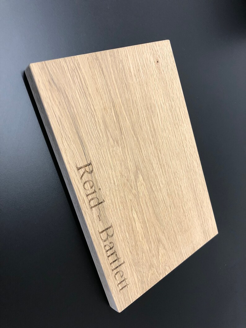 May include: A light brown wooden cutting board with the name "Reid - Bartley" engraved on the surface.