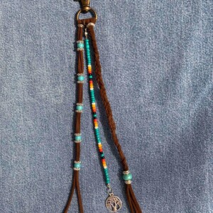 May include: A brown leather keychain with turquoise and multi-colored beads, a tree charm, and a metal clasp.