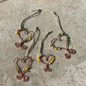 May include: Four copper wire heart ornaments with green and yellow beads. Each heart has a twine loop for hanging.