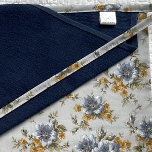 May include: A white ceramic mug with a black handle and the text "But First, Coffee" in a bold, black font. The mug is set against a blurred background, suggesting a cozy setting.