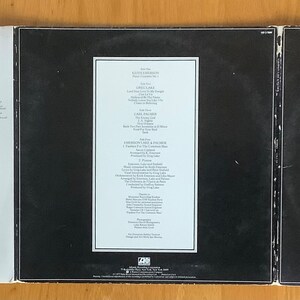 May include: A black vinyl record album cover with the title "WORKS" and the artist "EMERSON, LAKE & PALMER" in white text. The back of the album cover has a white label with the track listing and credits.