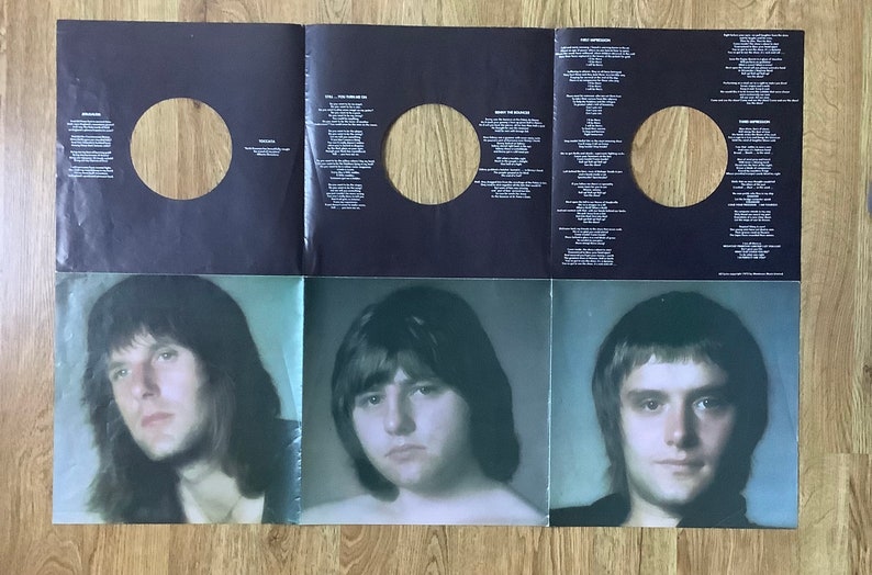 May include: A black and white vinyl record album cover with three men's portraits on the bottom half. The top half features three blank circles for the records and song lyrics.