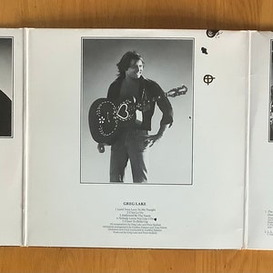 May include: A black and white photograph of a piano with a person sitting at the keys. The photo is on the left side of a record album cover. The right side of the cover features a black and white photograph of a man playing a guitar. The bottom of the cover has text listing the songs on the album.