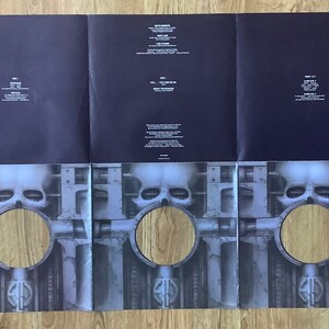May include: A three-panel gatefold vinyl record cover with a black background and a silver skull image on the front. The skull is surrounded by a metal structure with pipes and gears. The back panel features the album title "Fear of a Blank Planet" and the track listing. The record label is "EMI Records."