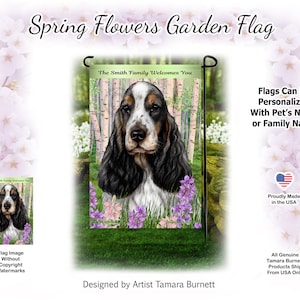 May include: A garden flag featuring a black and white Cocker Spaniel dog with brown markings, surrounded by purple and pink flowers. The flag has a green background with birch trees and the text "The Smith Family Welcomes You".