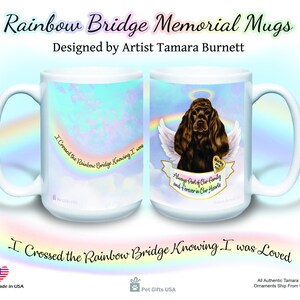 May include: White ceramic coffee mug with a rainbow bridge and clouds design. The mug features a brown and black Cocker Spaniel dog with angel wings and a halo. The text on the mug reads "I crossed the rainbow bridge knowing I was loved." and "Always part of our family and forever in our hearts."
