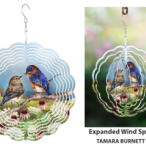 May include: A decorative wind spinner featuring a bluebird and a smaller brown bird perched on a branch with flowers. The spinner has a layered, scalloped design with a hanging hook. The text "Expanded Wind Spinnie" is visible.