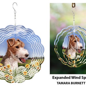 May include: A decorative wind spinner featuring a detailed portrait of a dog with brown and white fur, set against a backdrop of a field with yellow flowers and a blue sky. The spinner has a wavy, layered design.