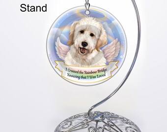 May include: White dog with angel wings on a round ornament with a rainbow and the text "I crossed the Rainbow Bridge Knowing that I was Loved". The ornament is on a silver metal display stand.