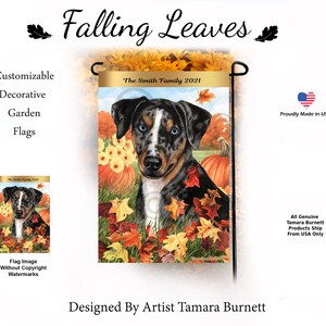 May include: A garden flag with a dog illustration, pumpkins, and autumn leaves. The flag displays "Falling Leaves" and "The Smith Family 2021". Designed by Artist Tamara Burnett, it's proudly made in the USA. The flag is a decorative garden item.