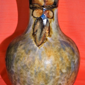 May include: A brown and blue ceramic vase with a mottled glaze and a decorative design of stylized flowers and leaves.