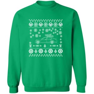 May include: Green sweatshirt with a white holiday design. The design includes a car with a Christmas tree on top, snowflakes, steering wheels, and Christmas trees. A festive and seasonal apparel item.