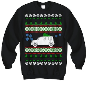 May include: Black Christmas sweater with a white car carrying a green Christmas tree. The sweater has a red and green snowflake pattern.