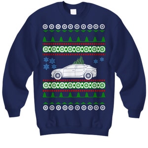 May include: A navy blue Christmas jumper with a white car carrying a Christmas tree on top. The jumper has a red and green snowflake pattern.