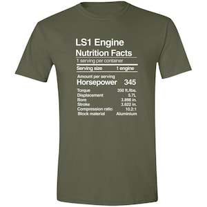 Puede incluir: Camiseta verde oliva con texto blanco. El texto dice "LS1 Engine Nutrition Facts" e incluye especificaciones del motor como potencia, par, cilindrada, diámetro, carrera, relación de compresión y material del bloque.