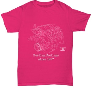 Puede incluir: Camiseta magenta con un dibujo lineal blanco de un motor. El texto "Hurting feelings since 1997" está impreso debajo del diseño del motor. La camiseta tiene cuello redondo y mangas cortas.