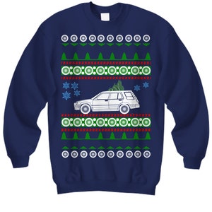 May include: A navy blue Christmas sweater with a white car carrying a Christmas tree. The sweater has a red and green patterned design with snowflakes.