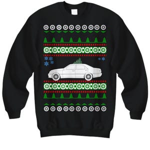 May include: Black sweatshirt with a festive design. The design includes a white car with a Christmas tree on top, surrounded by green trees, red and green circles, snowflakes, and white wheels. The top and bottom of the design have white circles.